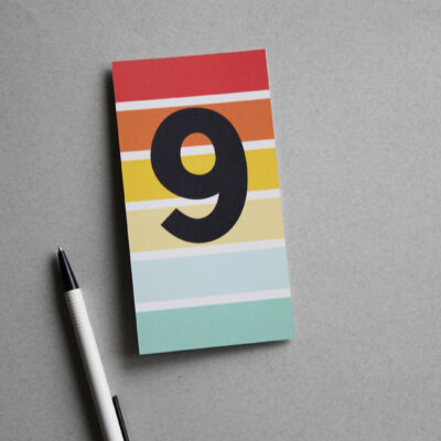 Postkarte bunt gestreift mit der Ziffer 9